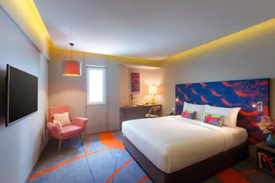 a bedroom with a large bed and a chair at Tinidee Trendy Bangkok Khaosan in Bangkok