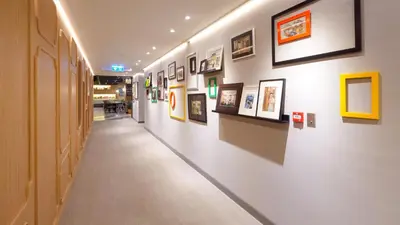 a hallway with paintings and pictures on a wall at Tinidee Trendy Bangkok Khaosan in Bangkok