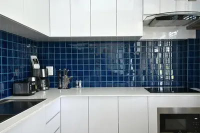 a kitchen with white cabinets and blue tiles on the wall at Green Lung Pool Villas Bangkok in Bang Krasop