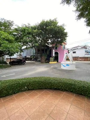 a green hedge in front of a pink building at เดอะวิลล่า71 รีสอร์ท in Ban Zong Katiam