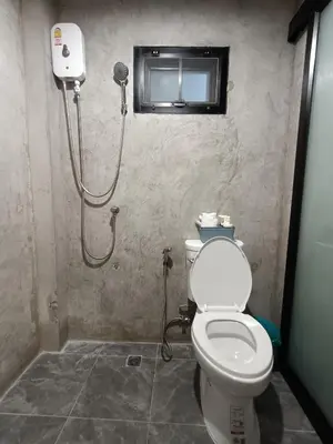 a bathroom with a toilet and a shower at The Loftel Resort in Bangkok