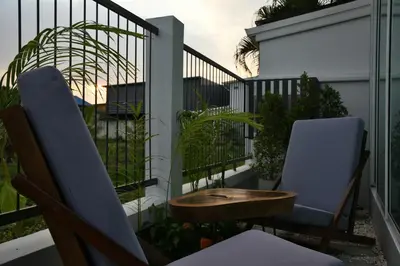 a balcony with two chairs and a wooden table at Green Lung Pool Villas Bangkok in Bang Krasop