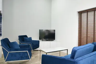 a living room with blue chairs and a tv at Green Lung Pool Villas Bangkok in Bang Krasop