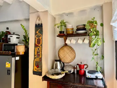 a kitchen with a wooden table with plants on it at Baan KhaoSoi - Private room in a rooftop hostel 2nd floor in Khlong San