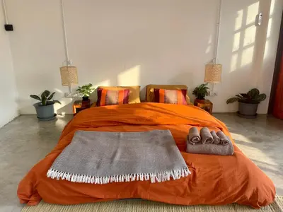 an orange bed with two pairs of shoes on it at Baan KhaoSoi - Private room in a rooftop hostel 3rd floor in Khlong San
