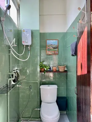 a green tiled bathroom with a toilet and a shower at Baan KhaoSoi - Private room in a rooftop hostel 4th floor in Khlong San