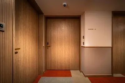a hallway with wooden doors in a building at Sotetsu Grand Fresa Bangkok in Bangkok