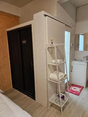 a room with a bed and a shelf with towels at Hommie by De-A-Ga in Ban Bang Talat