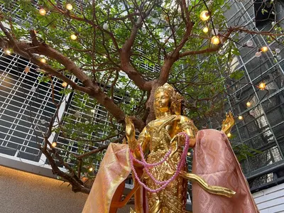 a gold statue next to a tree with lights at Rema residence China town Main Road in Bangkok