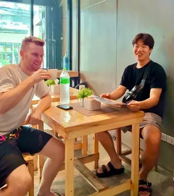 two men sitting at a table with a bottle of wine at 829 Backpack Bangkok BM B&B in Bangkok
