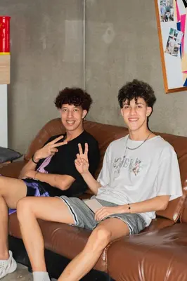 two young men sitting on a couch at COZY Bangkok BM B&B in Amphoe Phra Khanong