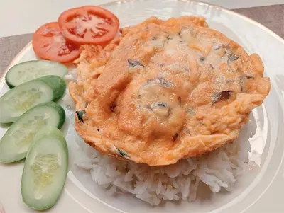 a plate with a pie and rice and tomatoes and cucumbers at COZY Bangkok BM B&B in Amphoe Phra Khanong