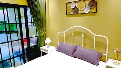 a bedroom with a white bed with purple pillows at BEB Silom Condolette in Bangkok