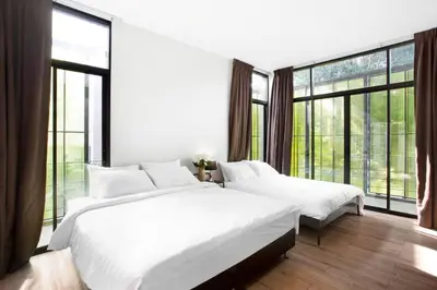 two white beds in a room with large windows at Bangkok Luxury Pool Villa Thonglor in Bangkok