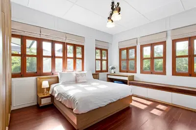 a bedroom with a bed and some windows at Sathorn Private Pool Villa in Bangkok