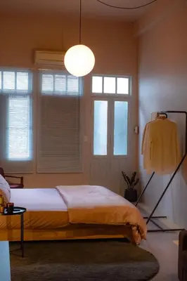 a bedroom with a bed and a lamp and windows at Cozy Room at The Coffee Store Charoenkrung in Bangkok