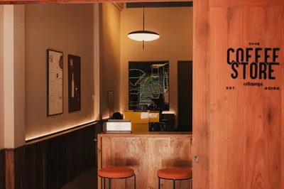 a coffee store with orange stools at a counter at Cozy Room at The Coffee Store Charoenkrung in Bangkok