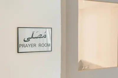 a sign for a prayer room on a white wall at Thomson Hotel Huamark in Bangkok