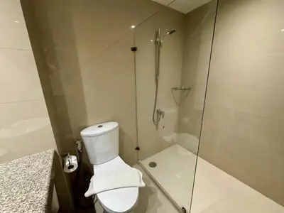 a bathroom with a toilet and a glass shower at Thomson Hotel Huamark in Bangkok