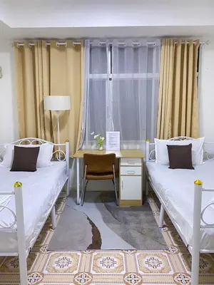 two beds in a room with a desk and a window at Guesthouse Station in Bangkok