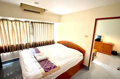 a bedroom with a bed with white sheets and a window at L'Hotel Bangkok in Bangkok