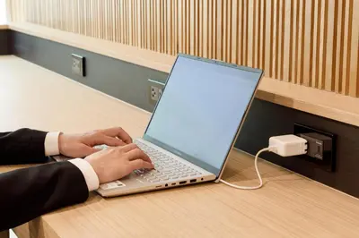 a person typing on a laptop computer on a table at Nishitetsu Hotel Croom Bangkok Silom in Bangkok