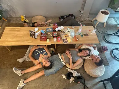 a group of people laying around a wooden table at Ti Thong Hostel in Bangkok