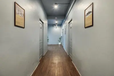 a hallway with white walls and wood floors and framed pictures at Ti Thong Hostel in Bangkok