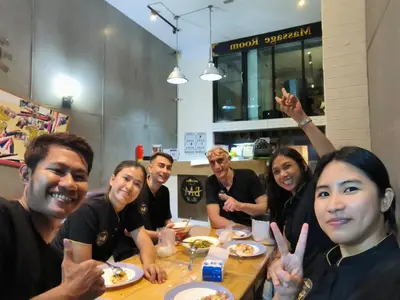 a group of people sitting at a table eating food at Guesthouse Bangkok BM B&B in Bangkok