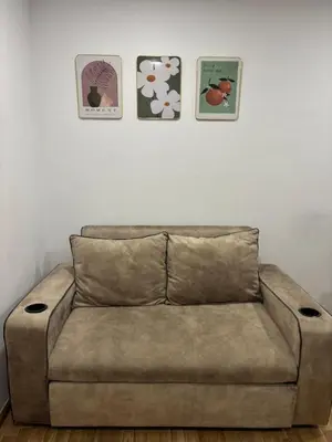 a brown couch in a room with three pictures on the wall at Sukhumvit​ 101 in Phra Khanong