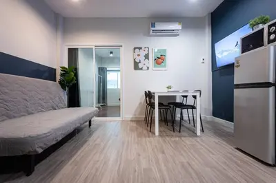a room with a bed and a table and a refrigerator at A2 Comfortable space wt Kitchen in Bangkok