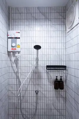 a shower in a white tiled bathroom with a shower at A3 Large Room, Full Facilities in Bangkok
