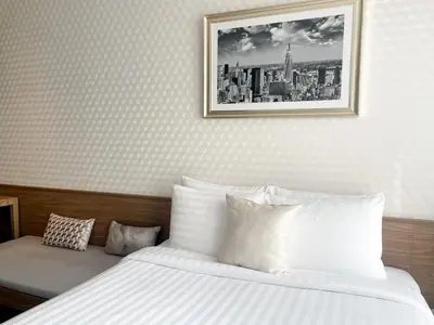 a bedroom with a white bed with a picture on the wall at Luxurious Apartment in Sukhumvit in Bangkok