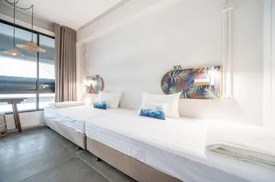 two twin beds in a room with a window at Unplugged at Bangrak Design Hostel in Bangkok