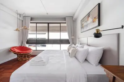 a bedroom with a large white bed with a window at Unplugged at Bangrak Design Hostel in Bangkok