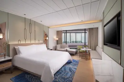 a bedroom with a large bed and a living room at Nysa Hotel Bangkok Sukhumvit 11 in Bangkok