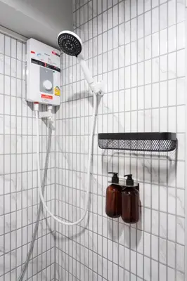 a white tiled wall with a shower head on a wall at A1 Duplex large room wt kitchen in Bangkok