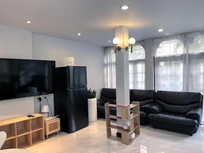 a living room with a black leather couch and a tv at Single house 4BR parking and kitchen in Sukhumvit49-1 in Bangkok