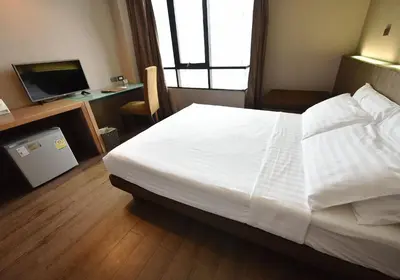 a bedroom with a large white bed and a television at Bangkok City Hotel in Bangkok