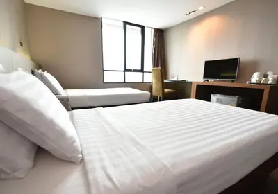 a hotel room with a large white bed and a desk at Bangkok City Hotel in Bangkok