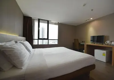 a bedroom with a large white bed with a window at Bangkok City Hotel in Bangkok