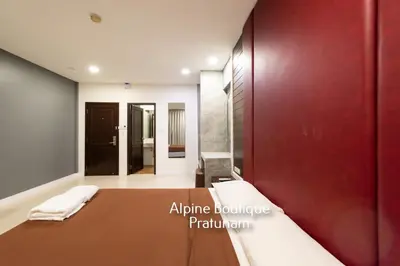 a bedroom with a bed and a red wall at Alpine Boutique Pratunam in Bangkok