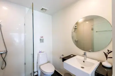 a white bathroom with a sink and a mirror at Narastay @ Phrom Phong in Bangkok