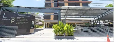 a building with awning on a street with plants in front at Lasalle Park Serviced Apartment at Lasalle 75 in Bangna