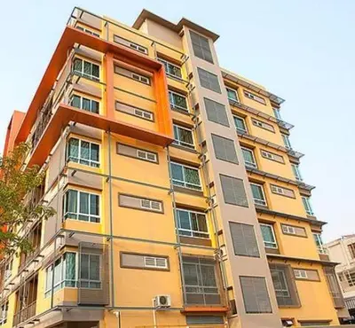 a tall yellow building with many windows at Lasalle Park Serviced Apartment at Lasalle 75 in Bangna