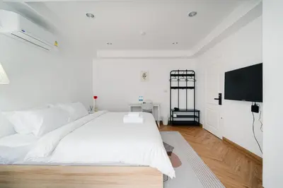 a white bedroom with a large bed and a flat screen tv at Mitt Haus (Lat Phrao Soi 5) in Bang Su