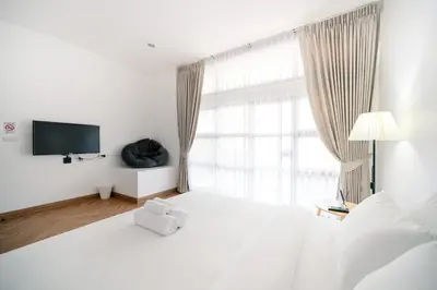 a white bedroom with a large bed and a television at Mitt Haus (Lat Phrao Soi 5) in Bang Su