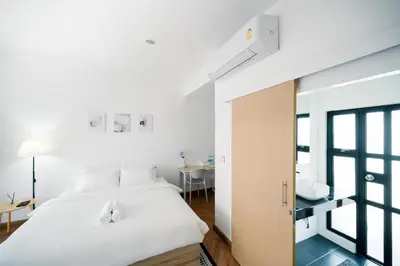a bedroom with a white bed and a desk at Mitt Haus (Lat Phrao Soi 5) in Bang Su
