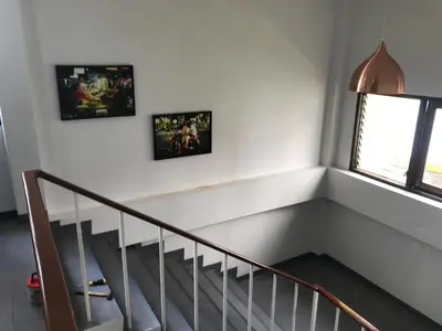 a staircase with two pictures on the wall and a window at Manoo House H in Makkasan