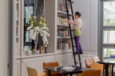 a woman standing on a ladder in a book shelf at U Sathorn Bangkok in Bangkok